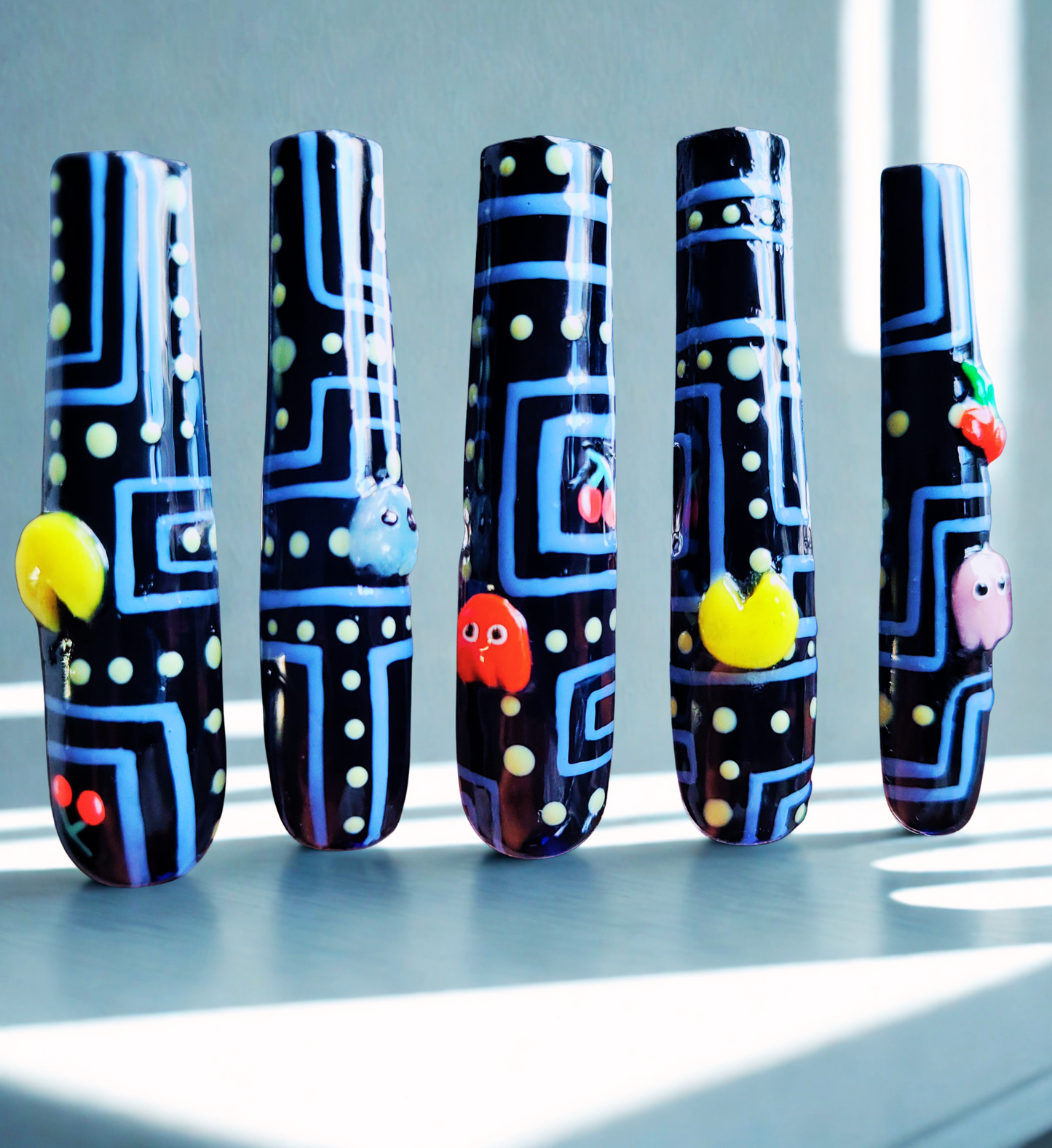 Five nail art designs inspired by retro arcade machine on a light background