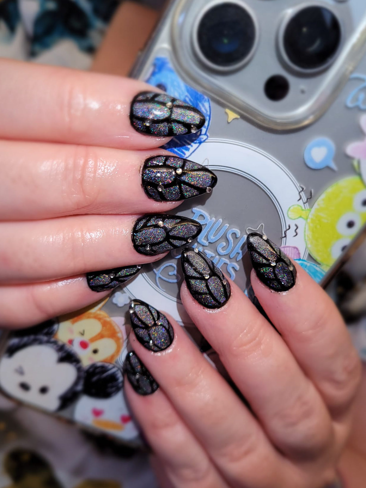 Close-up of hands with black nail art against a colorful phone case background
