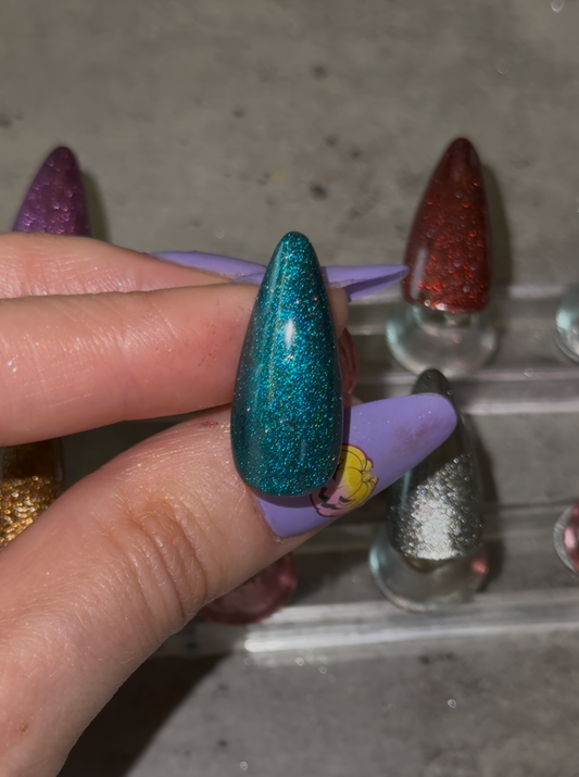 Colorful glittery nail polish samples on a gray surface