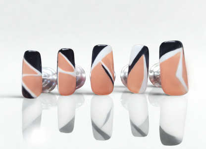 Set of nails with black, white, and peach design on a white background